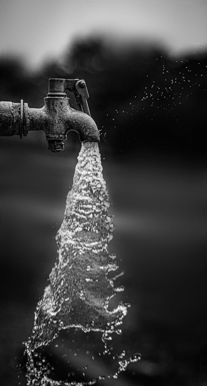 black and white shot of water flowing from a tap